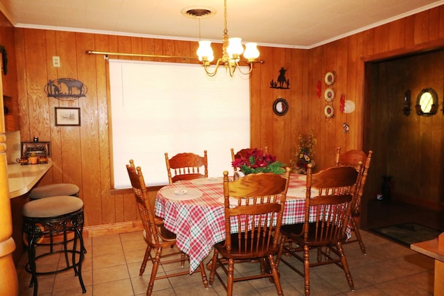 tiled dining area with wood walls, crown molding, and a chandelier