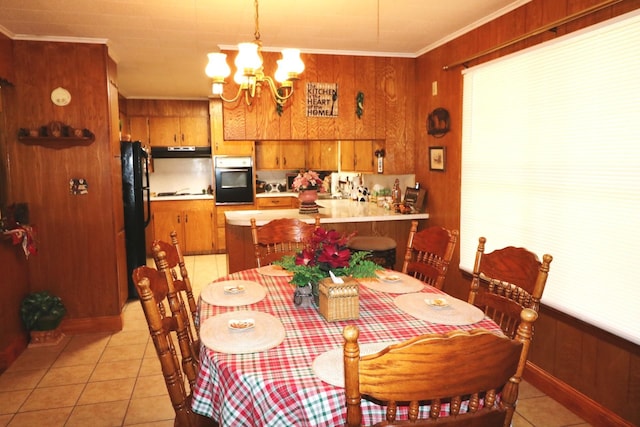 tiled dining area featuring ornamental molding, wooden walls, and an inviting chandelier