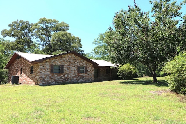 view of side of home featuring central AC unit and a lawn