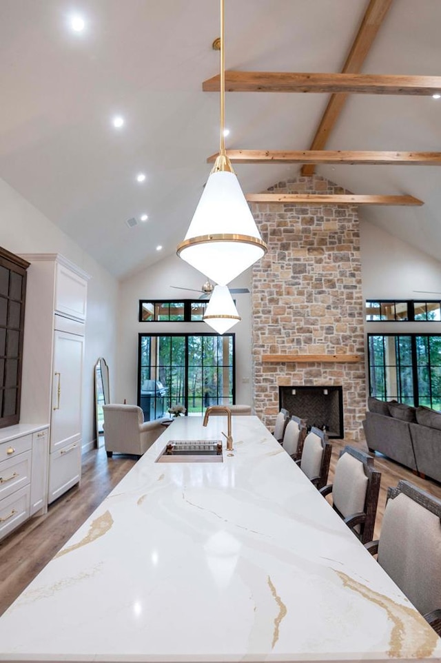 dining room featuring wood finished floors, beamed ceiling, high vaulted ceiling, recessed lighting, and a brick fireplace