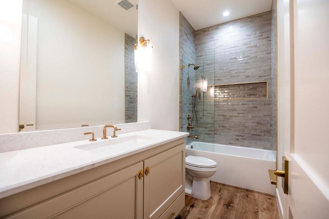 full bath with visible vents, toilet, wood finished floors, washtub / shower combination, and vanity