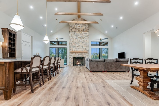 interior space featuring beamed ceiling, a healthy amount of sunlight, light wood-style flooring, and a fireplace