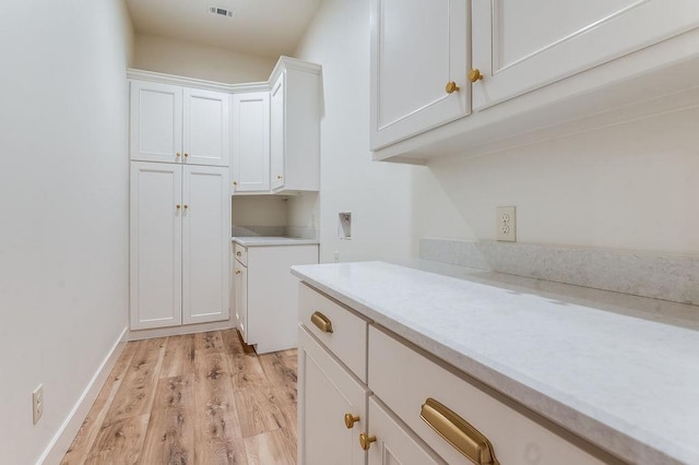 washroom with light wood-style flooring, cabinet space, and baseboards