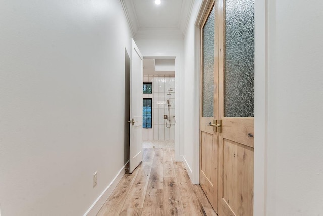 hall with crown molding, light wood-style flooring, and baseboards