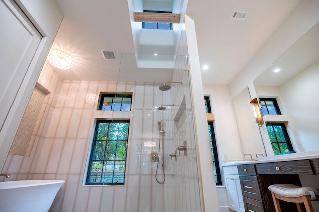 bathroom with visible vents, vanity, and a tile shower