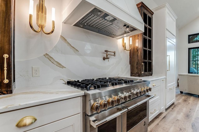 kitchen featuring light wood-type flooring, custom range hood, double oven range, radiator, and white cabinets