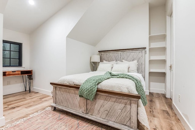 bedroom with light wood finished floors, baseboards, and vaulted ceiling