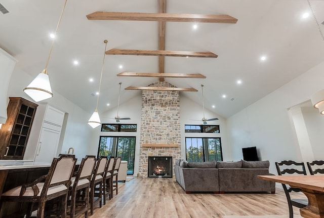 living area featuring visible vents, beamed ceiling, a healthy amount of sunlight, and light wood-style floors