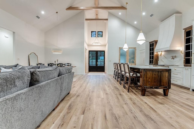 living room with light wood-type flooring, visible vents, beam ceiling, high vaulted ceiling, and baseboards