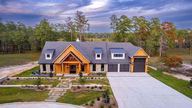 view of front of home featuring a front yard, driveway, a standing seam roof, an attached garage, and metal roof