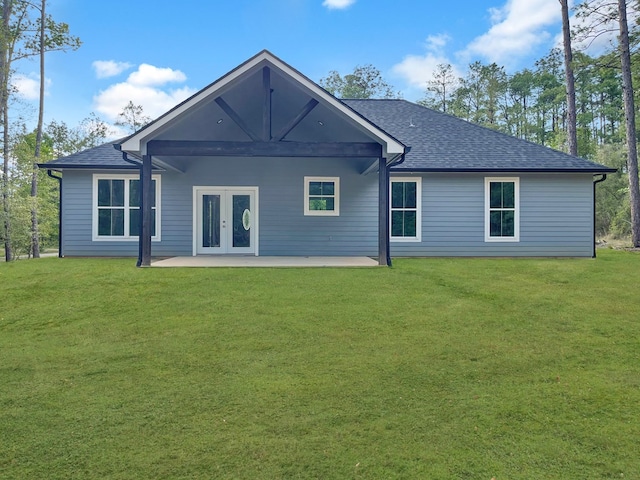 back of property featuring a patio area, a shingled roof, and a yard