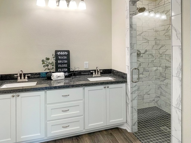full bathroom featuring wood finished floors, a sink, double vanity, and a stall shower