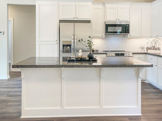 kitchen with white cabinets, stainless steel appliances, a center island, tasteful backsplash, and dark wood-style flooring