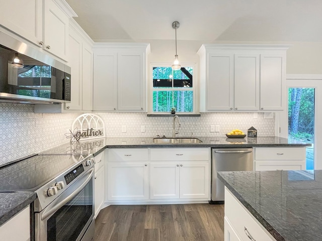 kitchen with white cabinets, stainless steel appliances, a sink, dark stone counters, and dark wood-style flooring