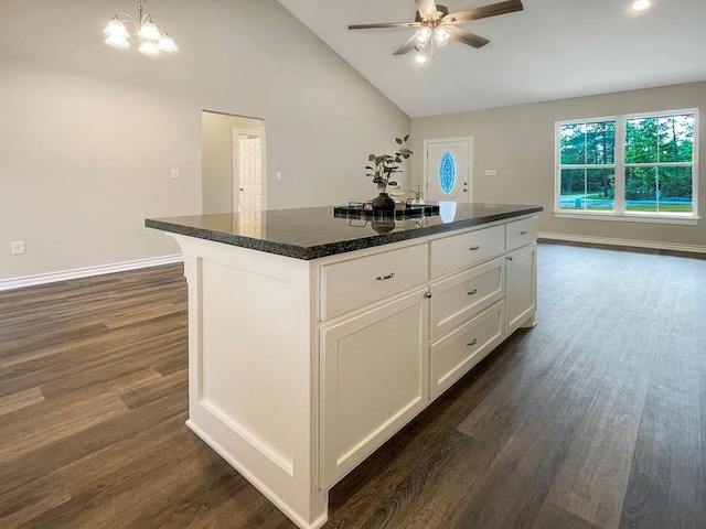 kitchen with a center island, ceiling fan with notable chandelier, lofted ceiling, white cabinetry, and dark wood-type flooring