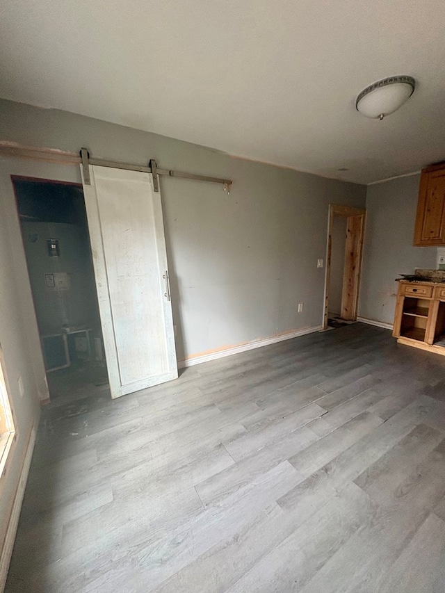 unfurnished living room featuring a barn door and light hardwood / wood-style flooring