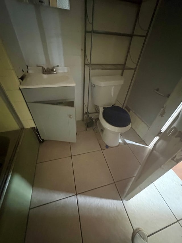 bathroom featuring tile patterned flooring, vanity, toilet, and walk in shower