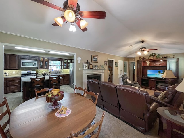 dining space with light tile patterned floors, vaulted ceiling, ceiling fan, and ornamental molding