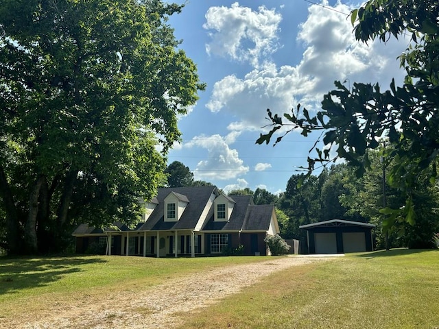 cape cod house with an outbuilding, driveway, a front yard, and a garage