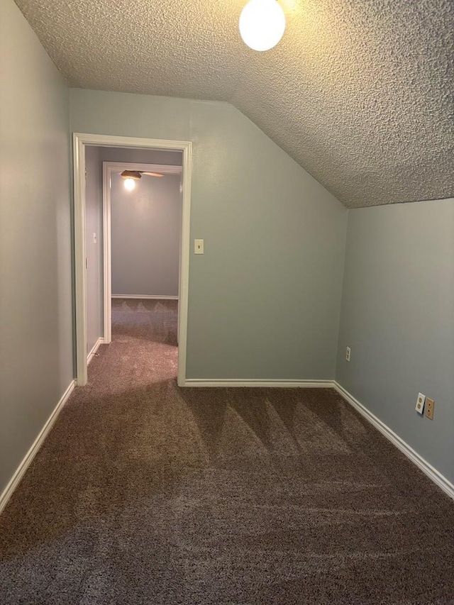 additional living space with carpet, vaulted ceiling, a textured ceiling, and baseboards