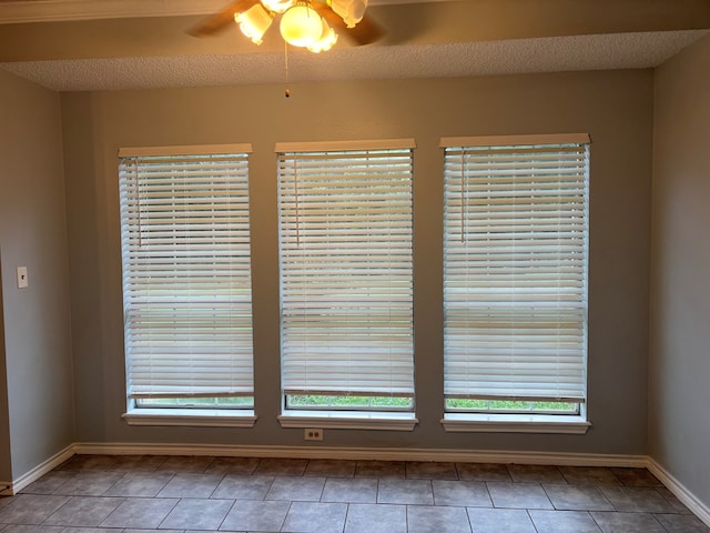 interior space featuring a textured ceiling, ceiling fan, and baseboards