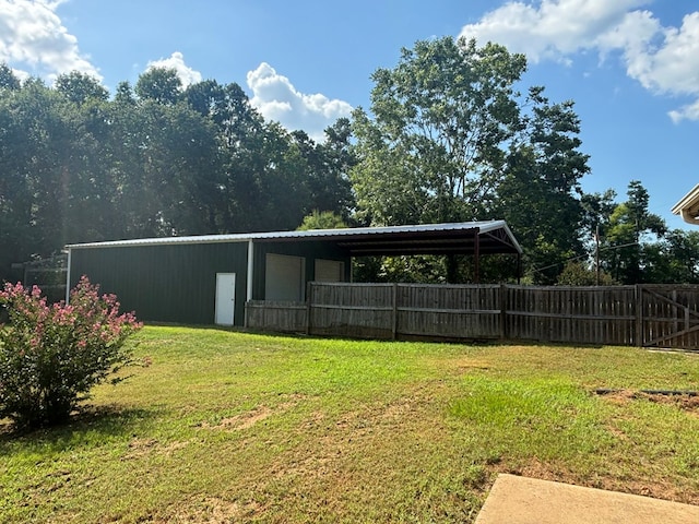 view of yard with a pole building, fence, a carport, and an outdoor structure