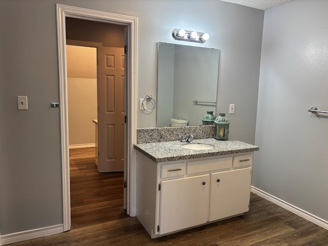 bathroom featuring baseboards, wood finished floors, and vanity