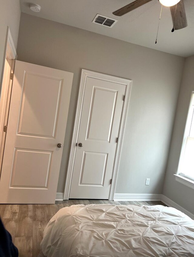 bedroom with a ceiling fan, light wood-style flooring, baseboards, and visible vents