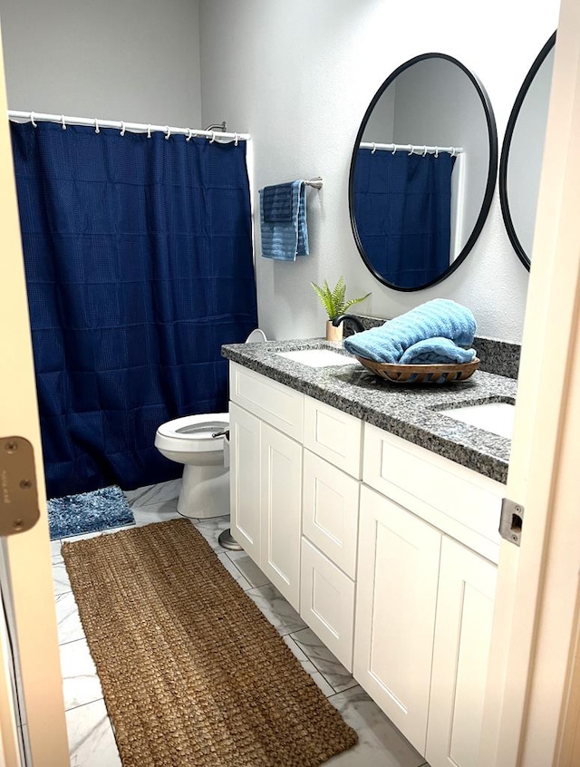 bathroom with double vanity, toilet, marble finish floor, and a sink