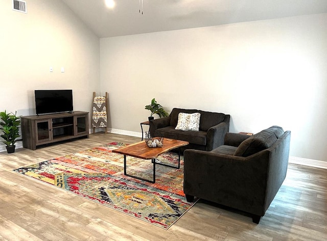 living area featuring lofted ceiling, wood finished floors, visible vents, and baseboards