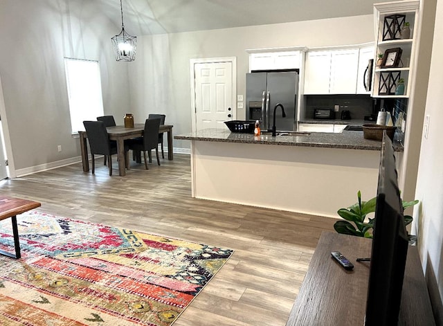 kitchen with light wood-type flooring, a sink, dark stone countertops, white cabinetry, and stainless steel appliances