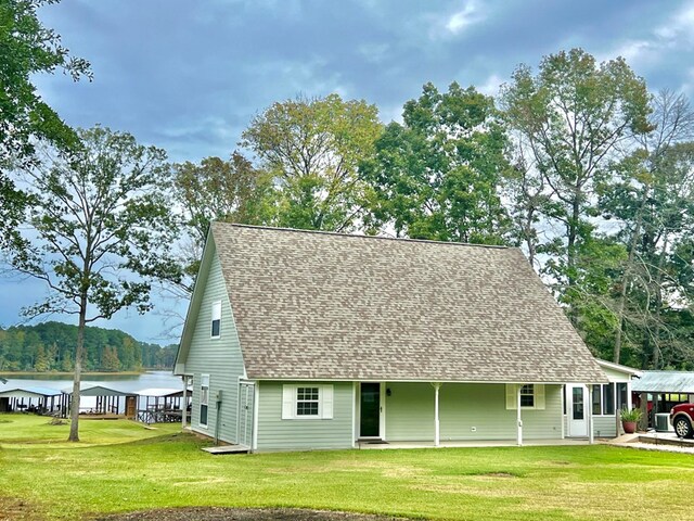 rear view of property with a lawn and a water view