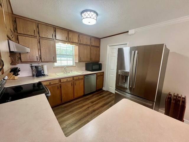 kitchen with appliances with stainless steel finishes, ornamental molding, a textured ceiling, sink, and dark hardwood / wood-style floors