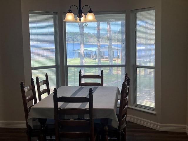 dining space with dark wood-type flooring and a notable chandelier