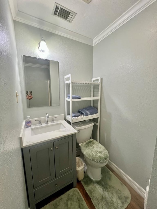 bathroom featuring toilet, vanity, wood-type flooring, and ornamental molding