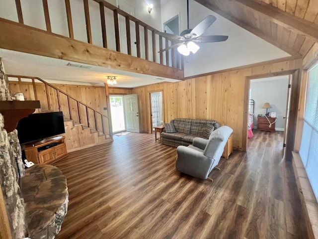 living room with beam ceiling, ceiling fan, high vaulted ceiling, dark hardwood / wood-style floors, and wooden walls