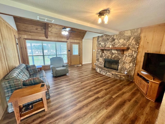 living room featuring ceiling fan, vaulted ceiling with beams, dark hardwood / wood-style floors, wooden walls, and a fireplace