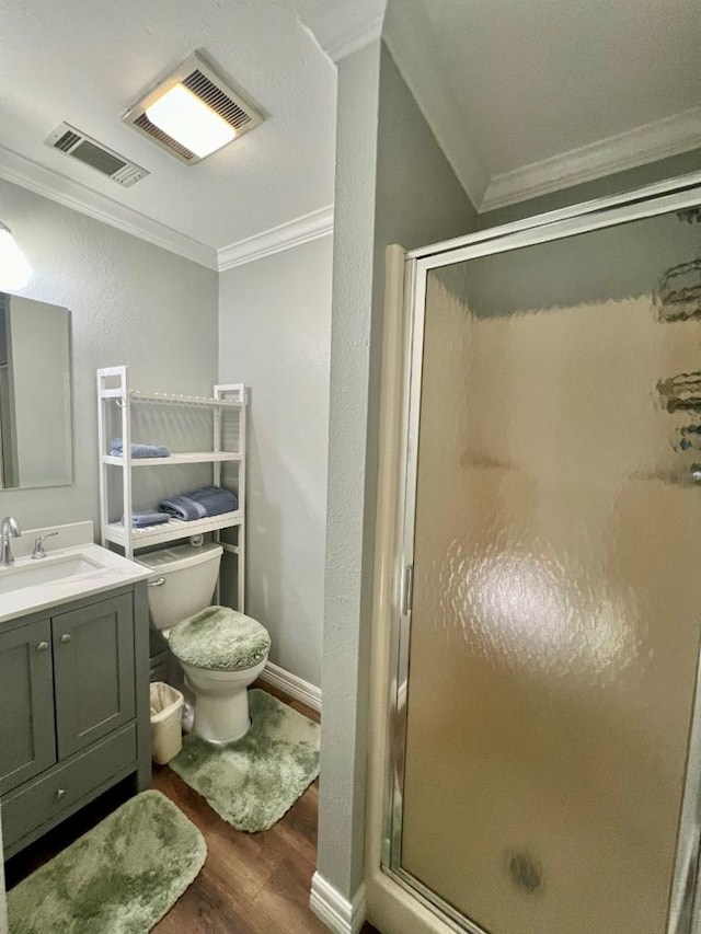 bathroom with vanity, a shower with door, crown molding, wood-type flooring, and toilet