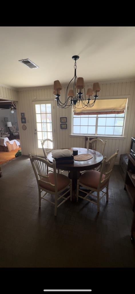 dining area with wooden walls, a chandelier, and a wealth of natural light