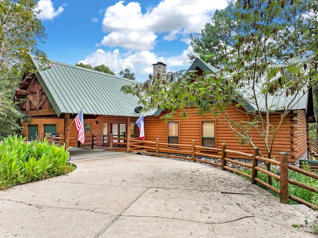 194 Woodsedge Dr, Brookeland, TX 75931 - log home featuring log exterior, concrete driveway, a chimney, and a metal roof