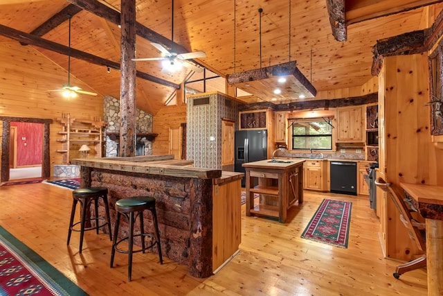 194 Woodsedge Dr, Brookeland, TX 75931 - kitchen with black appliances, wood walls, open shelves, light wood-type flooring, and a center island with sink