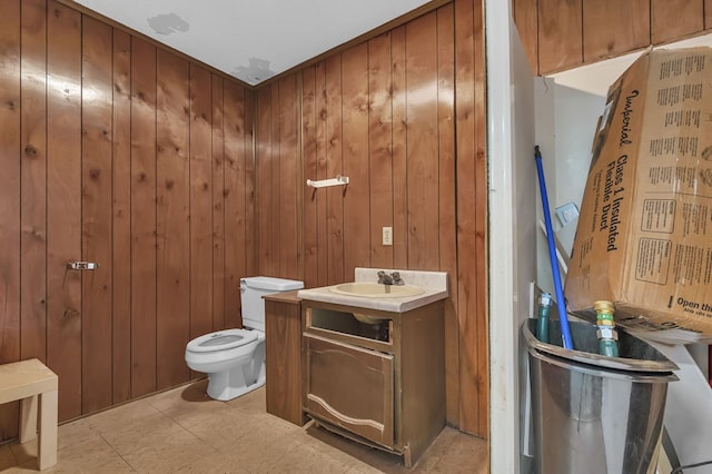 bathroom featuring vanity, toilet, and wood walls