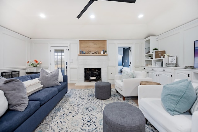 living room with ceiling fan, a fireplace, and light hardwood / wood-style flooring