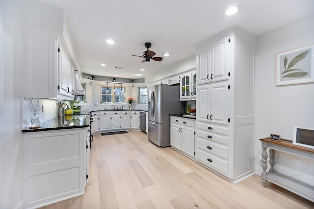 kitchen featuring appliances with stainless steel finishes, white cabinetry, decorative backsplash, ceiling fan, and light hardwood / wood-style floors