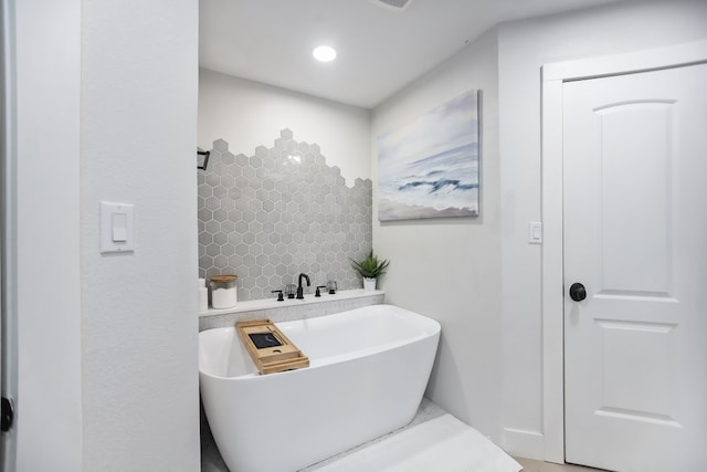 bathroom with decorative backsplash and a tub to relax in