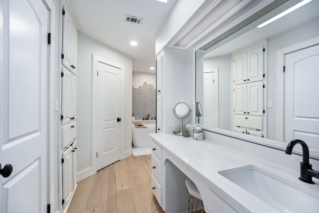 bathroom featuring a washtub, vanity, and wood-type flooring