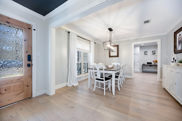 dining area featuring crown molding, a chandelier, and light wood-type flooring