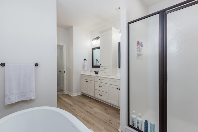 181 Rustic Pines Dr, Lufkin, TX 75904 - bathroom with wood finished floors, double vanity, a freestanding tub, a shower stall, and baseboards