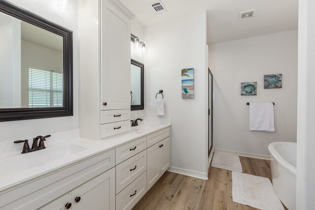 181 Rustic Pines Dr, Lufkin, TX 75904 - full bathroom with wood finished floors, double vanity, a freestanding bath, a stall shower, and baseboards