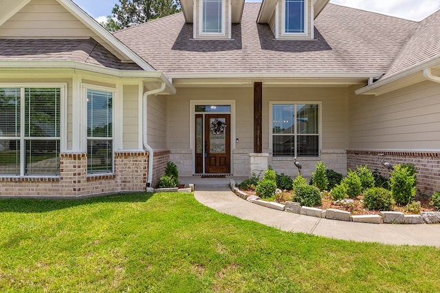 181 Rustic Pines Dr, Lufkin, TX 75904 - view of exterior entry featuring a yard, a shingled roof, and brick siding